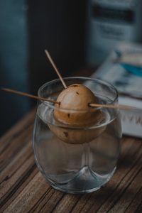 Close-up of an avocado seed suspended in water using toothpicks in a glass.